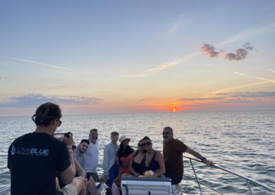 Group of people posing for a sunset photo on a boat with a LivBlue team member taking the picture.