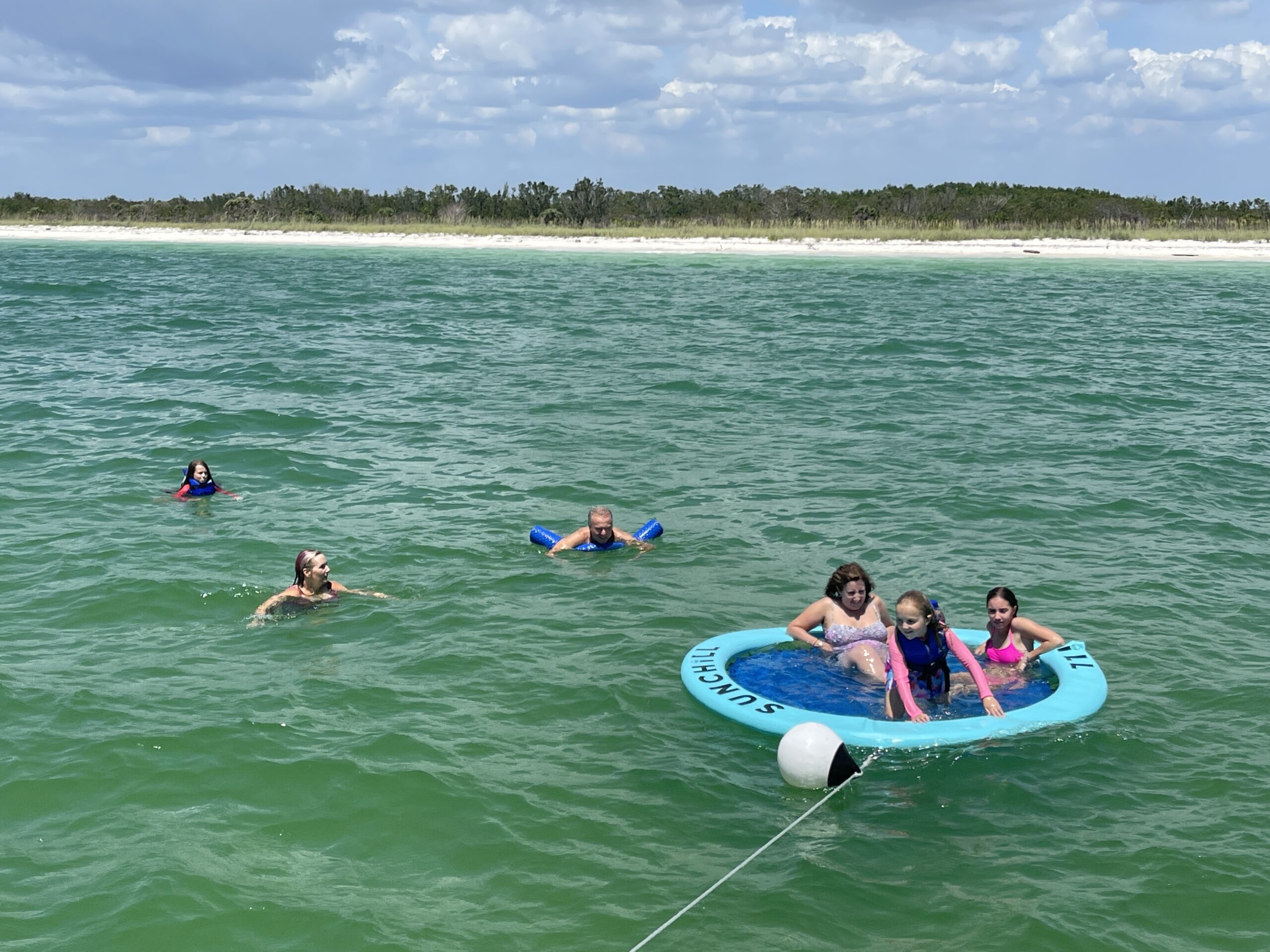 Family swimming off the coast of Naples, Florida during a Beach Club Charter with BRADventures yacht
