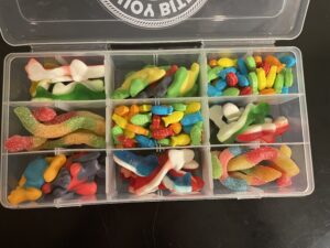 Kids Buoy Bites: Candy Catch Waterproof tackle box filled with colorful gummy candies including worms, sharks, fish, bones, and other assorted sweets