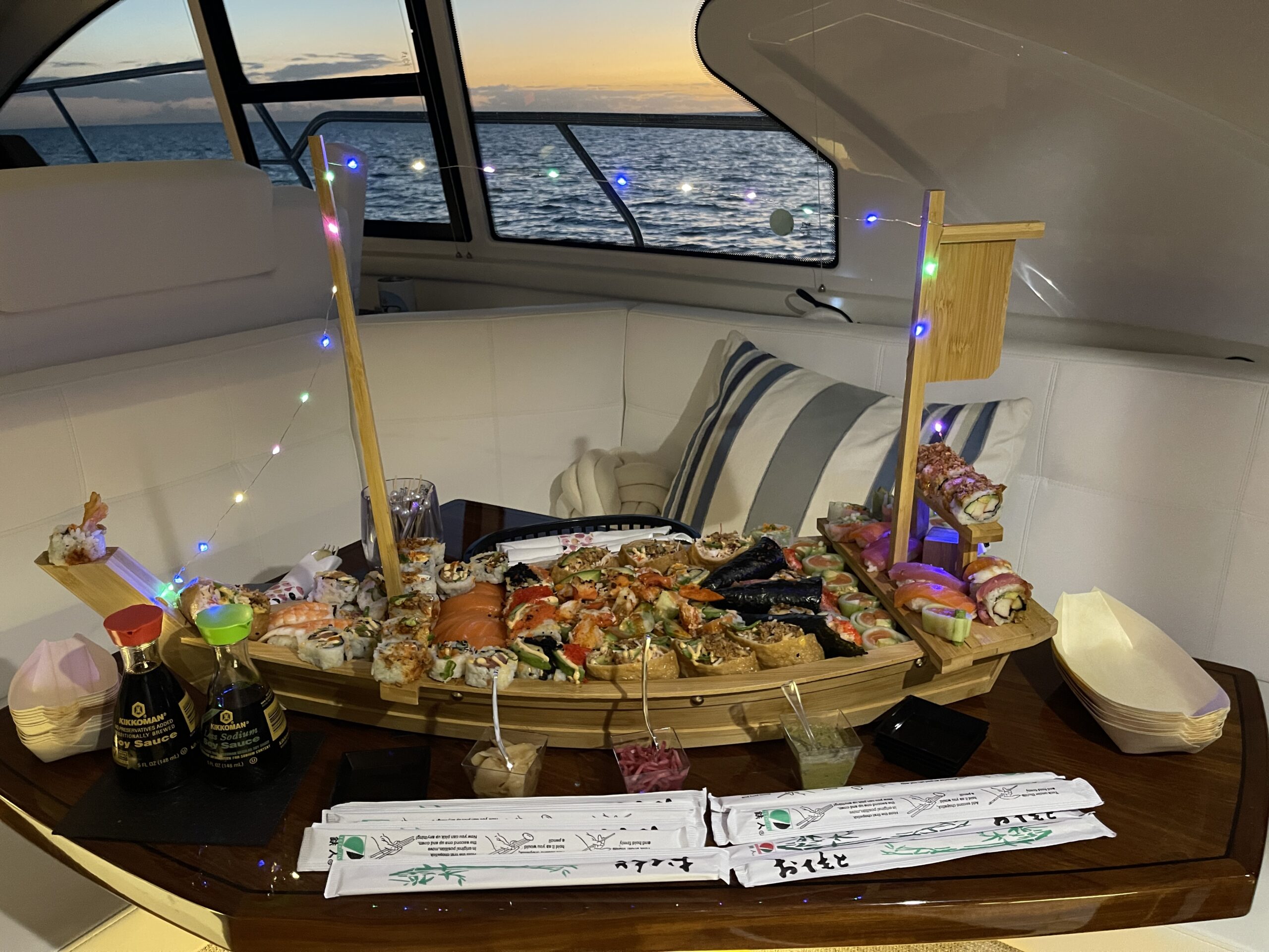 Sushi boat and gourmet setup inside a luxury yacht with ocean views at sunset