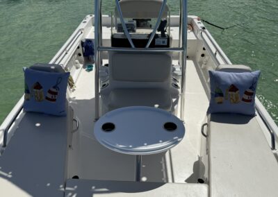 Interior of a center console boat with buoy-themed decorative pillows and a round table