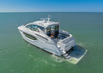 Rear view of Cruisers Cantius yacht with extended swim platform partially submerged in water, ready for swimming